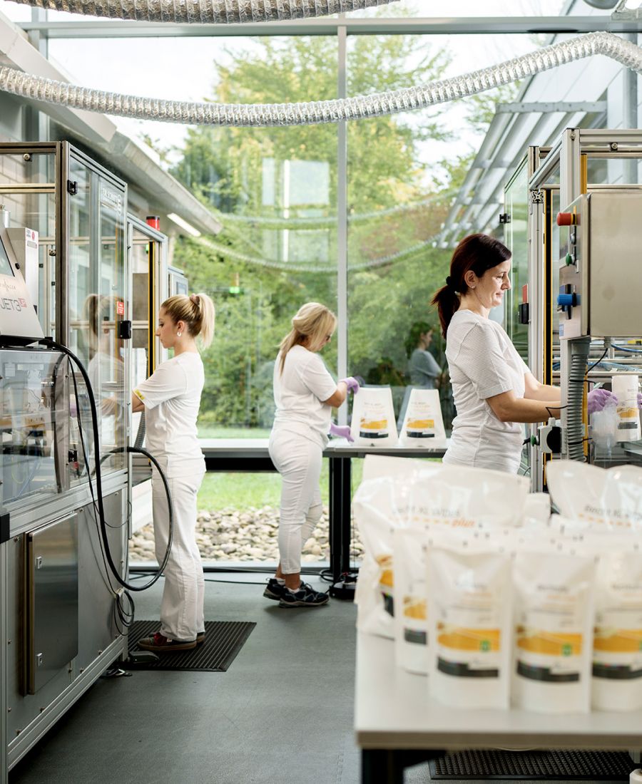 Mitarbeiterinnen der Alfred Becht GmbH arbeiten in einer modernen, lichtdurchfluteten Produktionshalle an Anlagen zur Herstellung von Medizinprodukten.