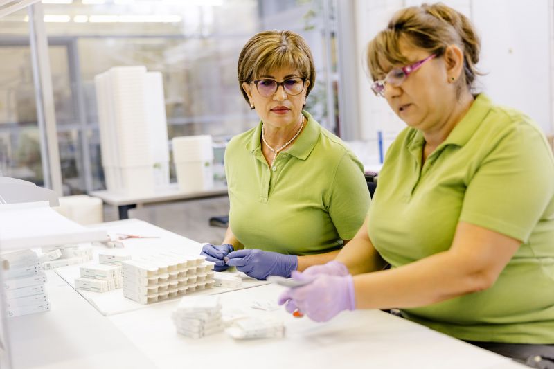 Zwei Mitarbeiterinnen der Alfred Becht GmbH kontrollieren und verpacken Medizinprodukte sorgfältig von Hand.