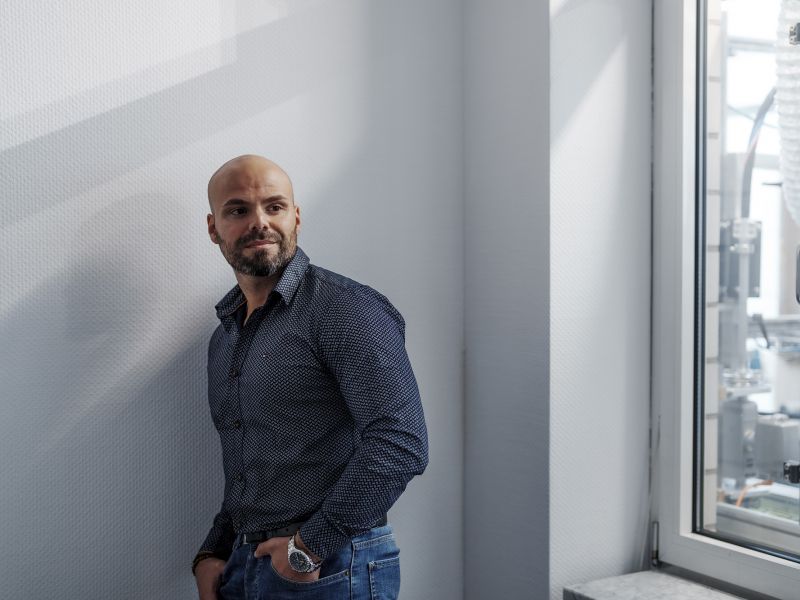 An employee of Alfred Becht GmbH stands casually by a window, looking outside.
