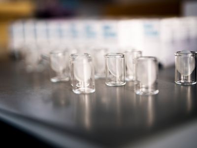 Transparente Glasbehälter aus der Produktion der Alfred Becht GmbH stehen in Reihen bereit für die weitere Verarbeitung.