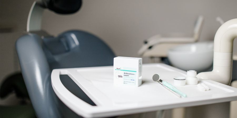 Zahnarzt Artikulationspapier und Stuhl-Setup Zahnarztstuhl mit Werkzeugen und Artikulationspapier auf einem Tablett, bereit für eine Patientenuntersuchung.