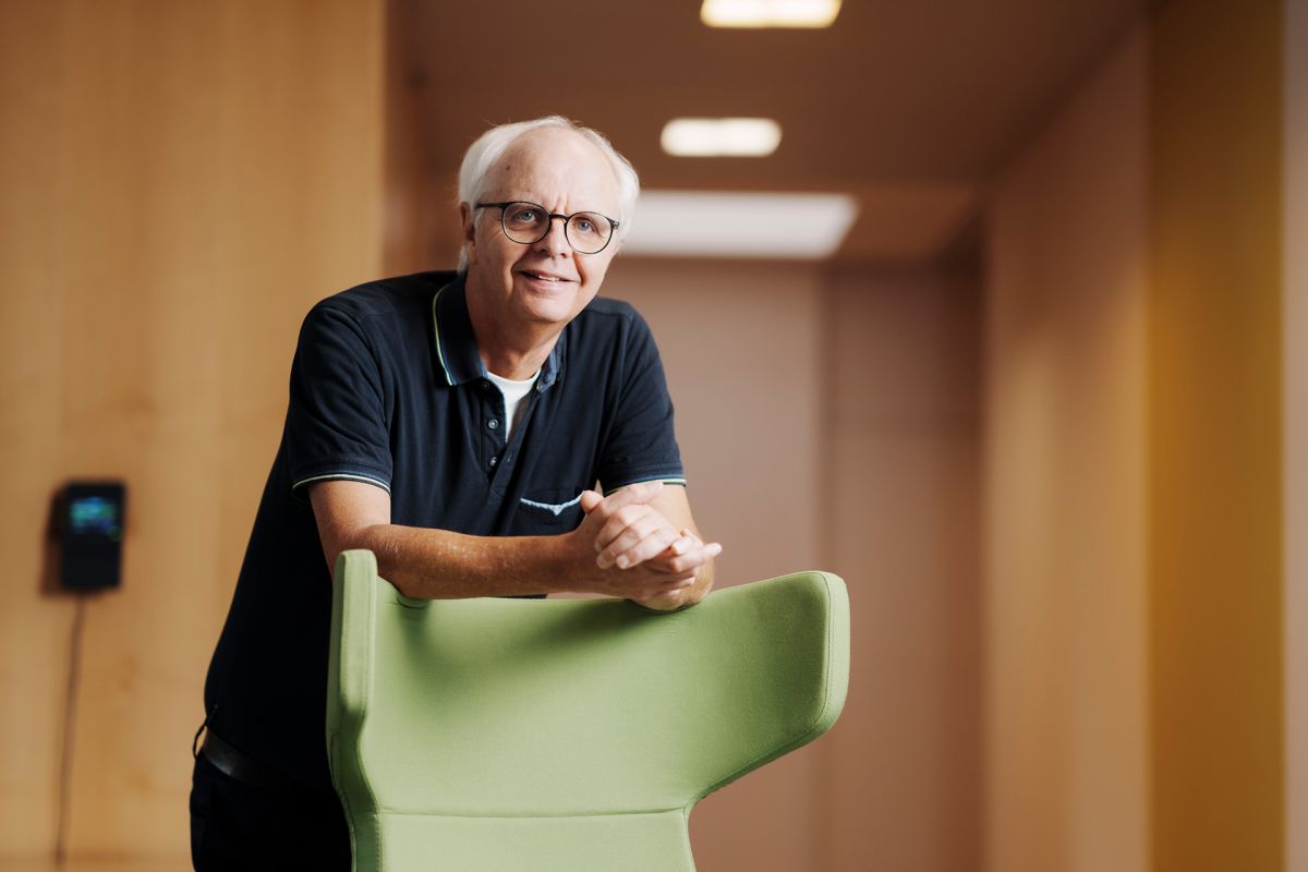 An employee of Alfred Becht GmbH stands smiling behind a green chair.