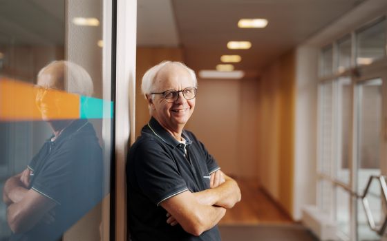 An employee of Alfred Becht GmbH stands with arms crossed by a glass wall, smiling at the camera.