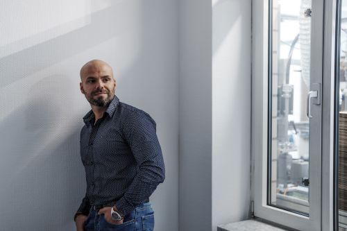 An employee of Alfred Becht GmbH stands casually by a window, looking outside.