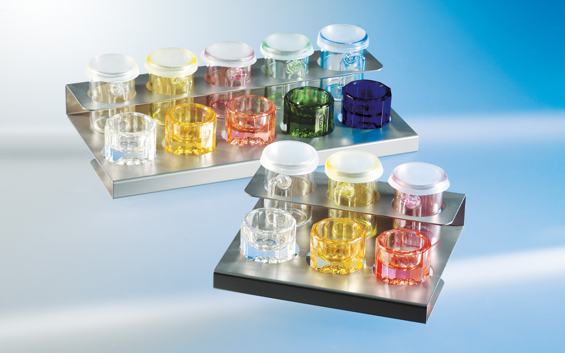 Alfred Becht Medi-Dispenser, colored glass containers with lids on a stainless steel holder.